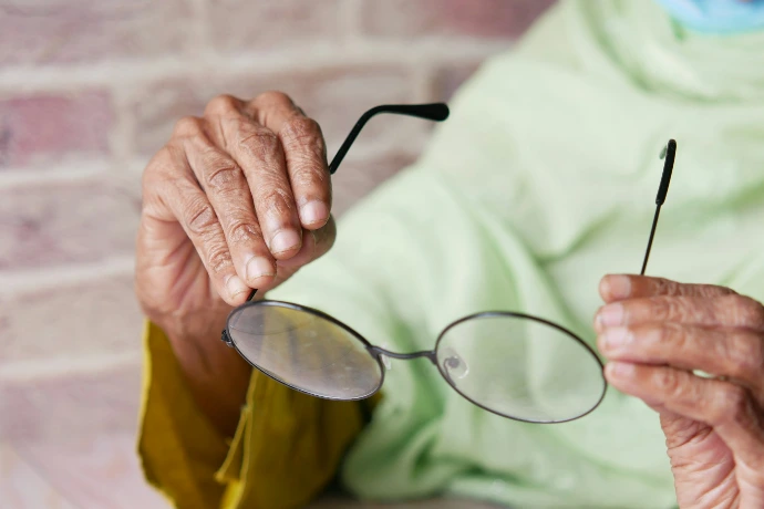 an elderly woman holding a pair of glasses